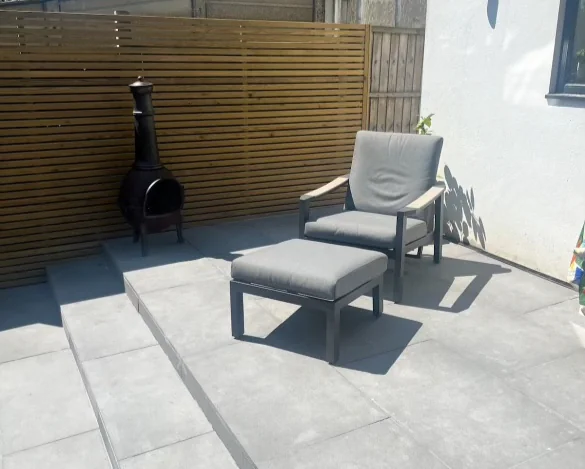 Raised light grey porcelain patio with steps in a Berrylands garden