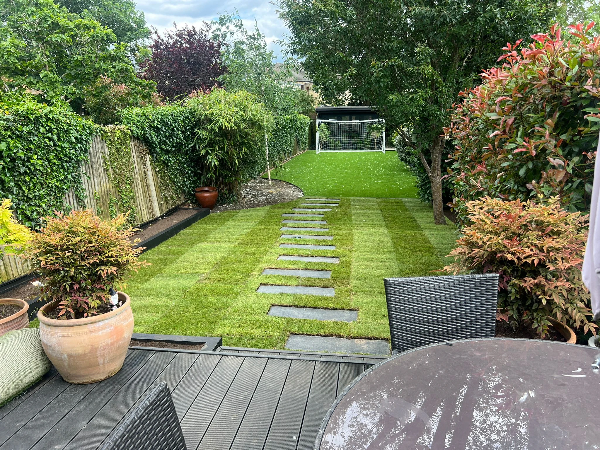 Family garden in Surbiton with natural turf, artificial grass and stepping stone path